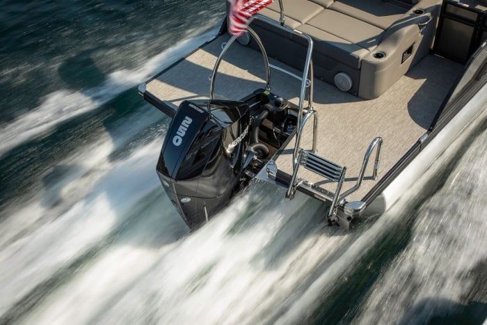 Outboard motor on a boat transom, with wake streaming behind in the water