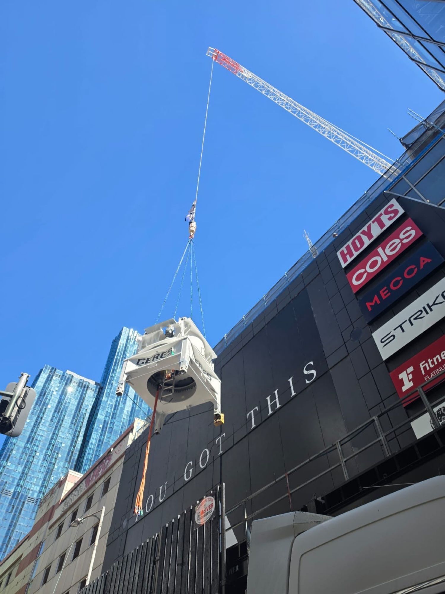 Crane lifting plant equipment past a Melbourne CBD building, supported by mobile hybrid power on site
