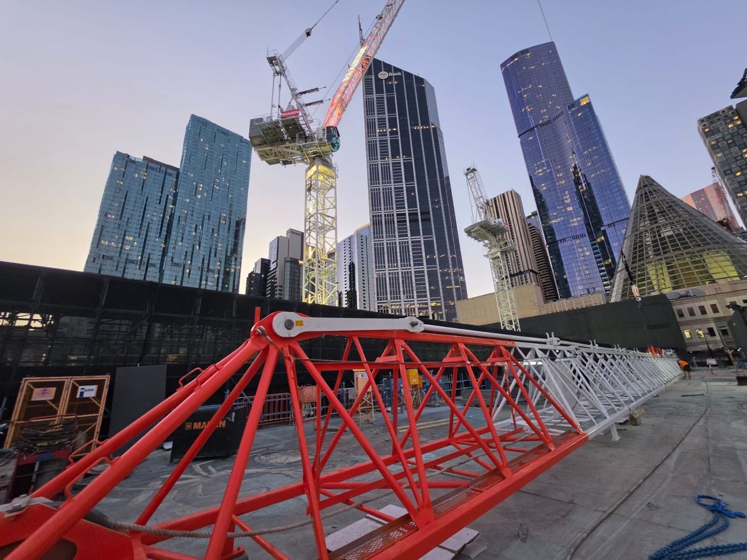 Tower crane jib on a Melbourne CBD construction site at dusk, where mobile hybrid power keeps site works running