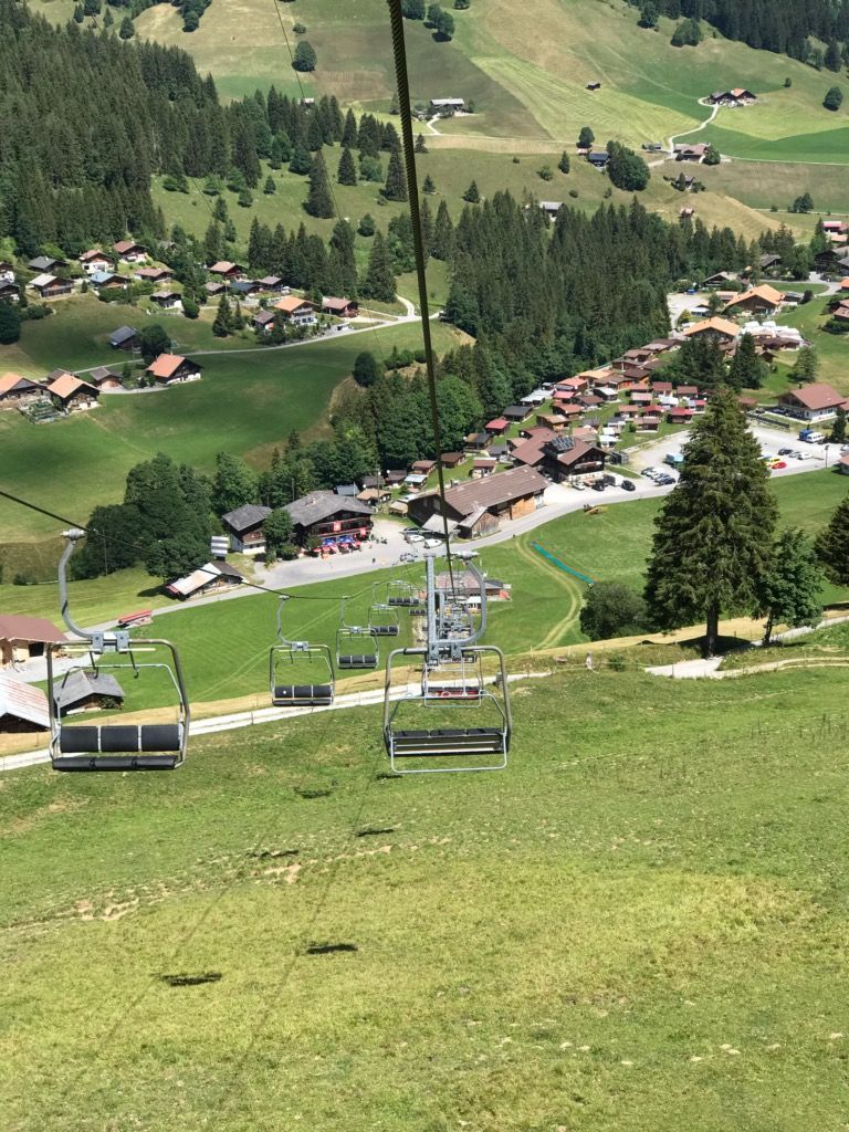Ein Skilift fährt einen grasbewachsenen Hügel in den Bergen hinauf.