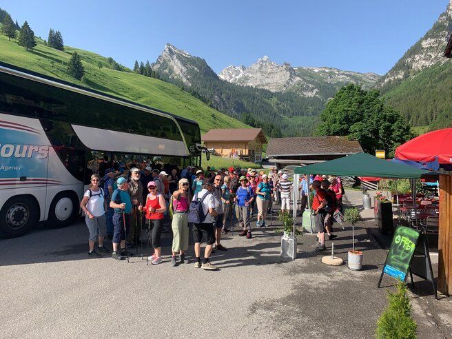 Eine Gruppe von Menschen steht in den Bergen vor einem Bus.