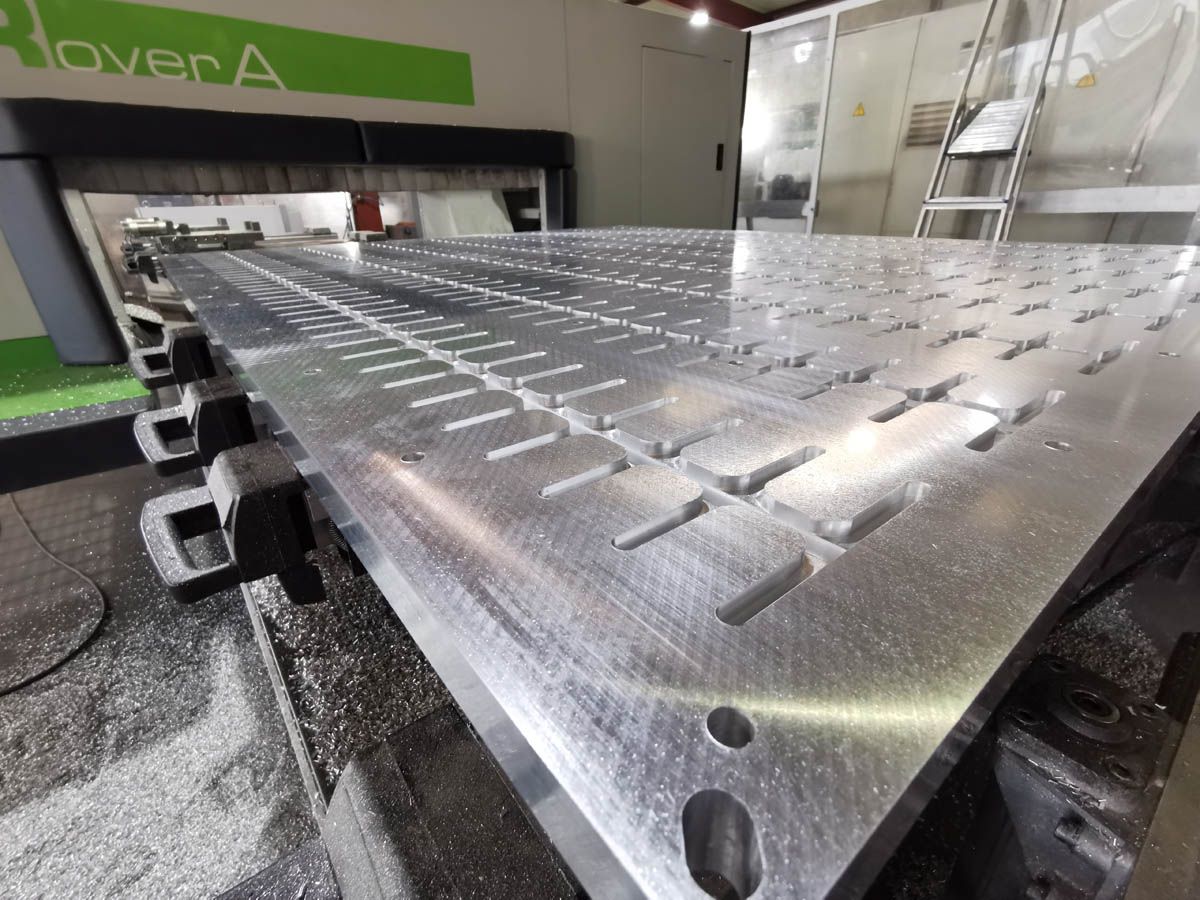 Metallblech mit Nuten auf einer CNC-Maschine, Rover A, in einer industriellen Umgebung.