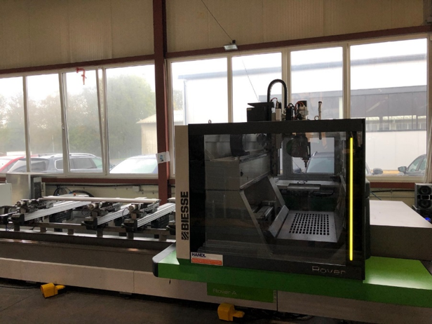 CNC-Maschine, grau und grün, in einer Fabrik, gläserne Sicherheitskabine, draußen nebliger Tag.