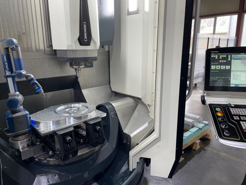 CNC-Fräsmaschine bearbeitet ein Metallteil; Bedienfeld und Messarm sind sichtbar.
