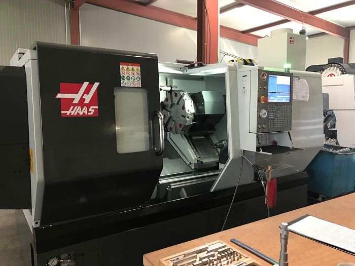 Schwarze und graue Haas CNC-Drehmaschine in einer Werkstattumgebung.
