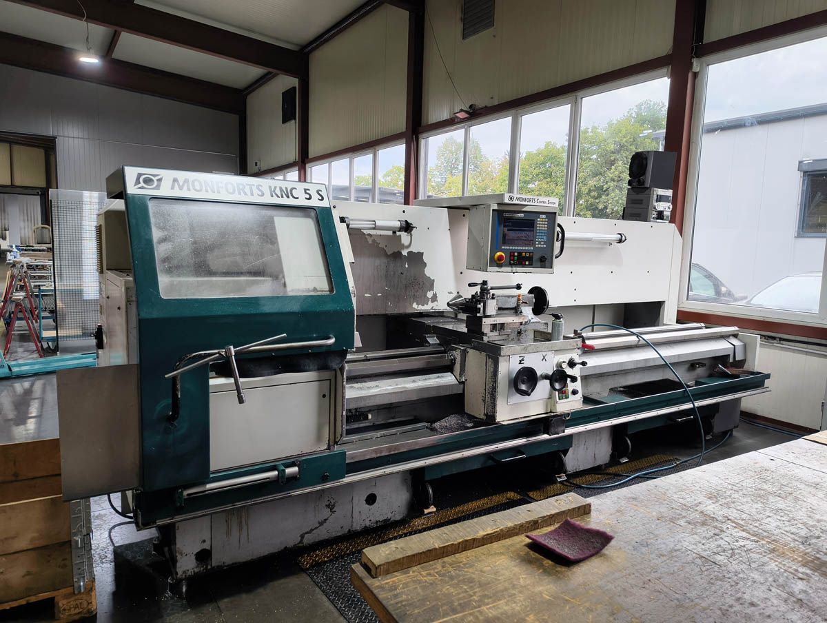 CNC-Drehmaschine in einer Werkstattumgebung, mit grünen und weißen Bauteilen.