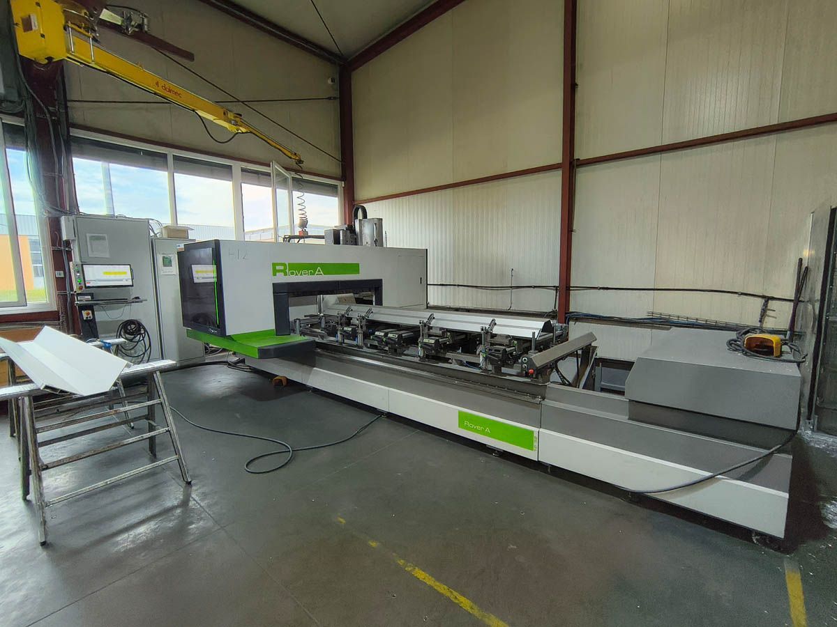 Große Industriemaschine in einer Fabrikumgebung, mit langem Tisch und Bedienfeld. Grüne und graue Farben dominieren.