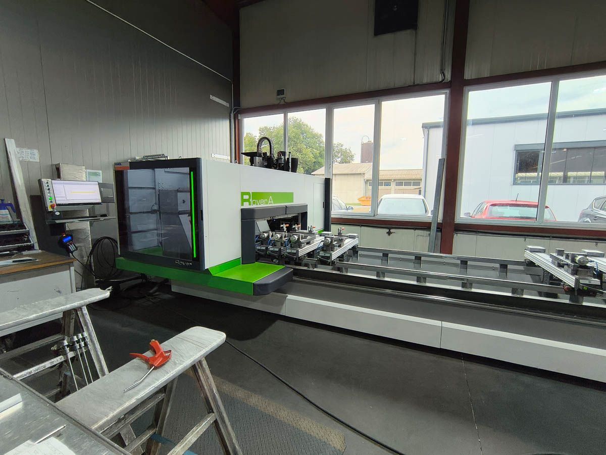 Eine grüne und weiße Industriemaschine in einer Werkstatt, neben den Fenstern.