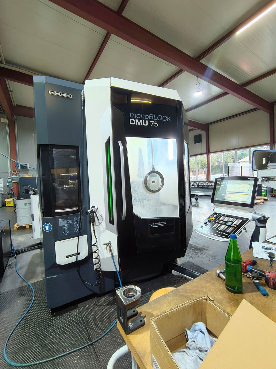 Große CNC-Maschine in einer Werkstatt, weiß und schwarz mit grünen Zierelementen.