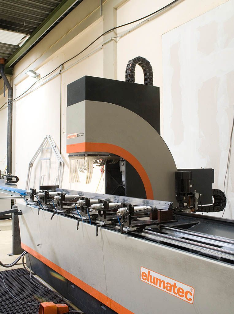 Industriemaschine der Marke Elumatec mit Metallstangen. Grau-schwarze Farbgebung, in einer Fabrikumgebung.