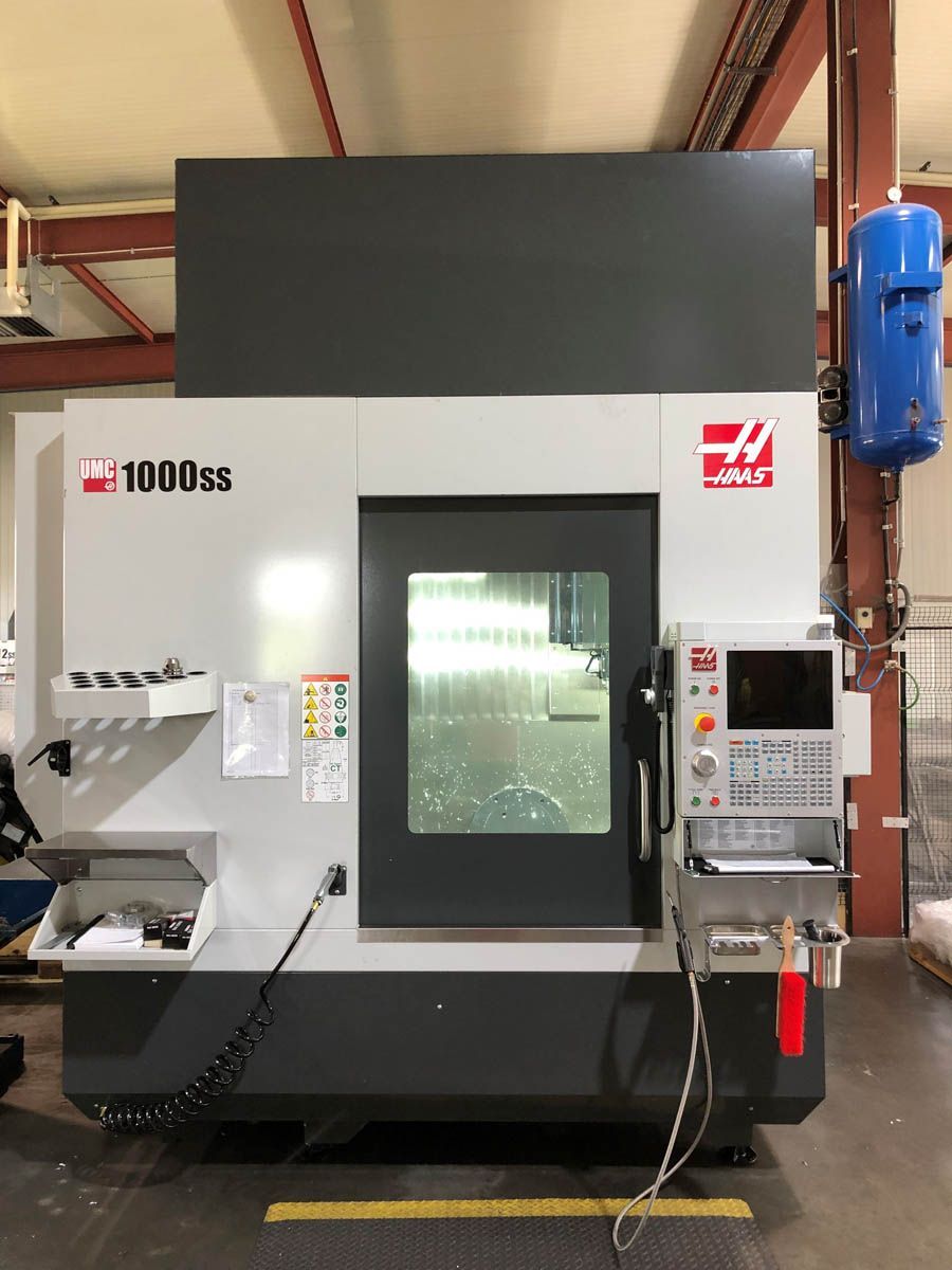Haas VF-1000SS CNC-Fräsmaschine in einer Werkstatt. Grau-weiße Maschine mit Bedienfeld und geschlossenem Arbeitsbereich.