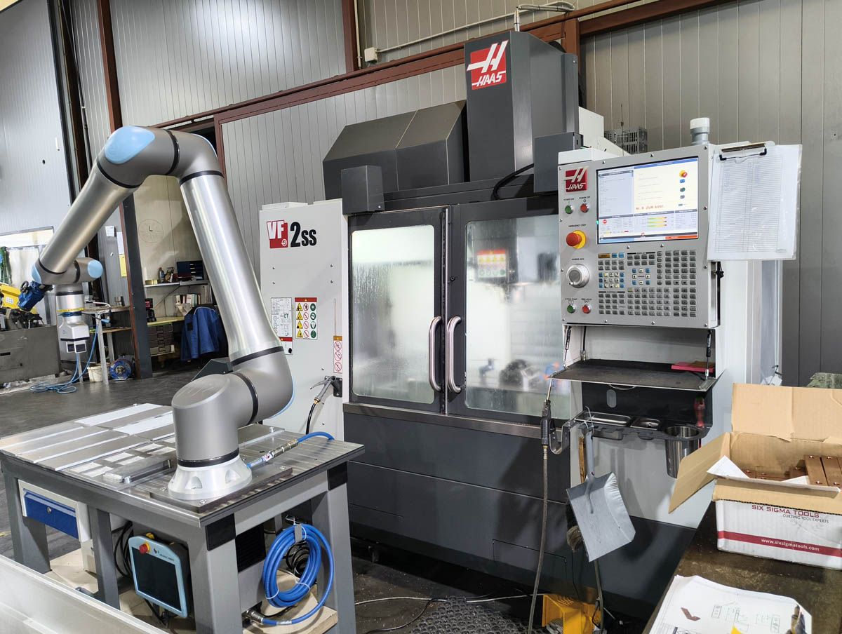 Ein Roboterarm lädt Teile in eine CNC-Maschine in einer Metallbearbeitungswerkstatt.