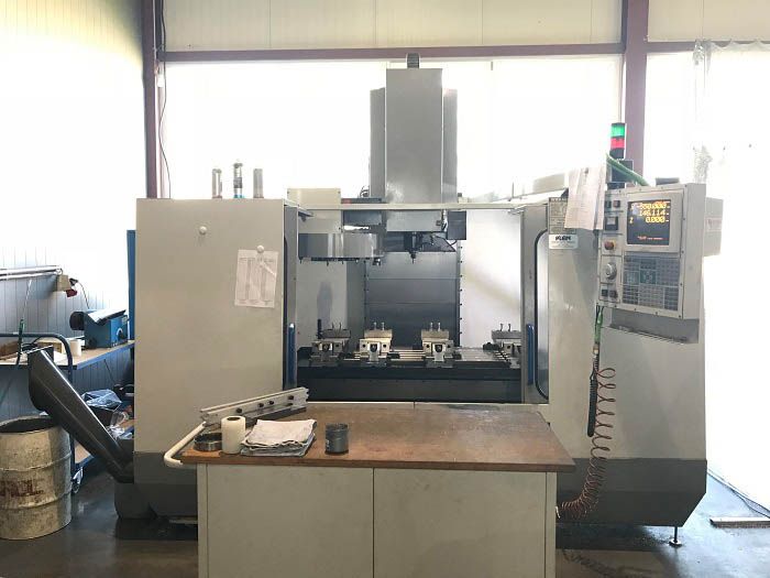 Große graue CNC-Maschine in einer Werkstattumgebung.