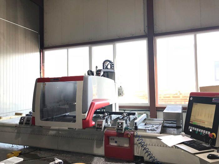CNC-Maschine in einer Werkstatt, rot und weiß, mit einem Computermonitor.