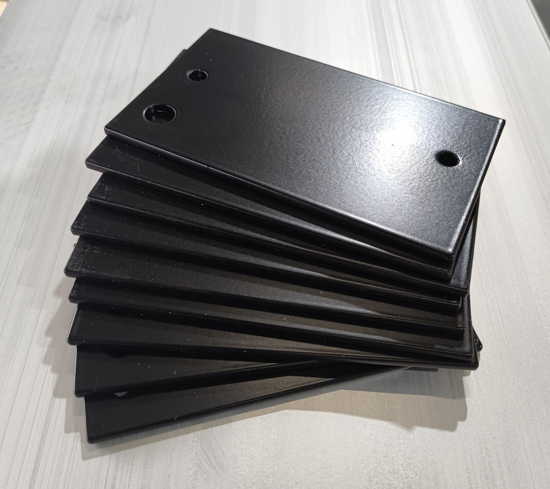 Stapel schwarzer, rechteckiger Metallplatten mit Löchern.