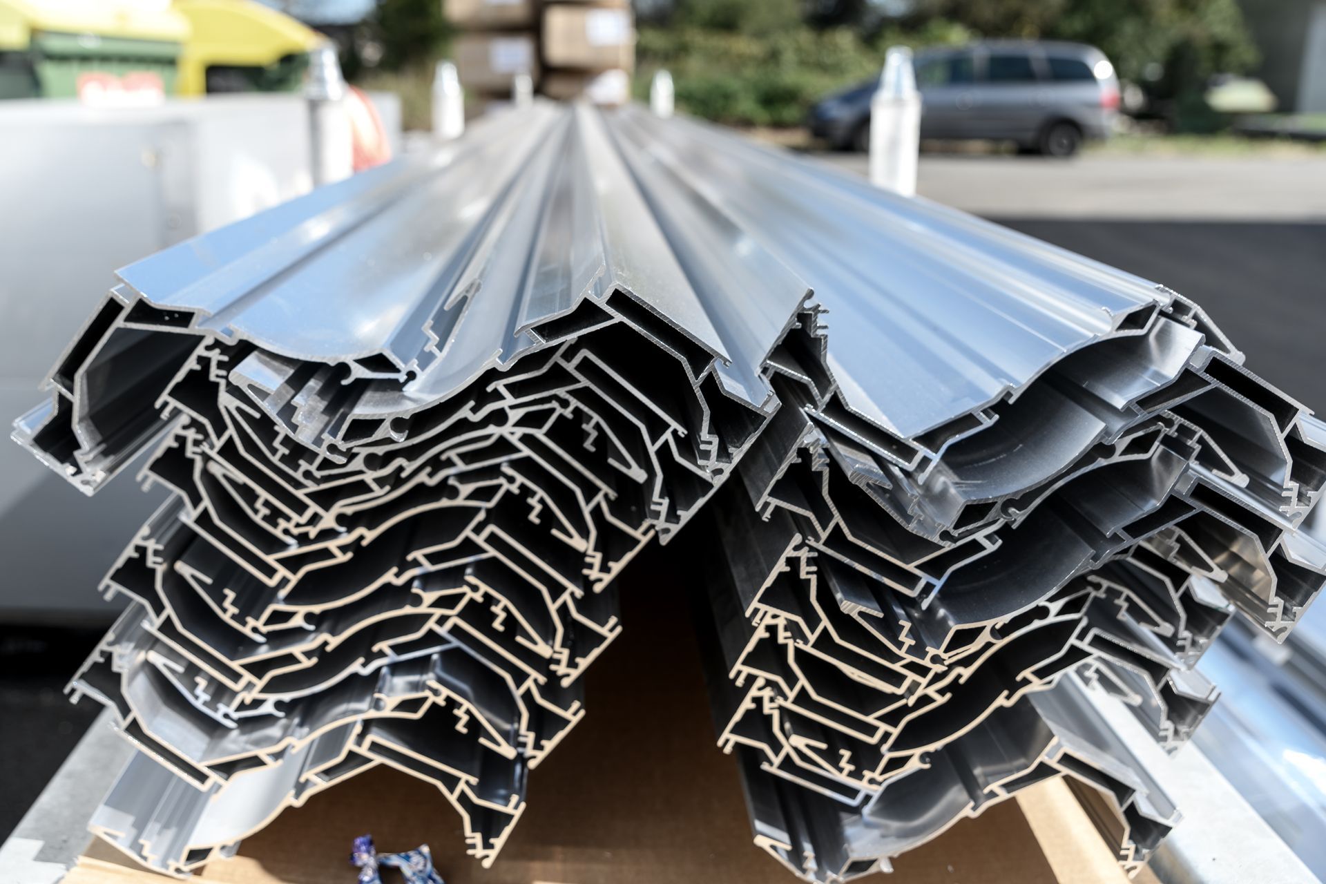 Stapel aus silbernen Aluminiumprofilen, abgewinkelte Profile sichtbar.