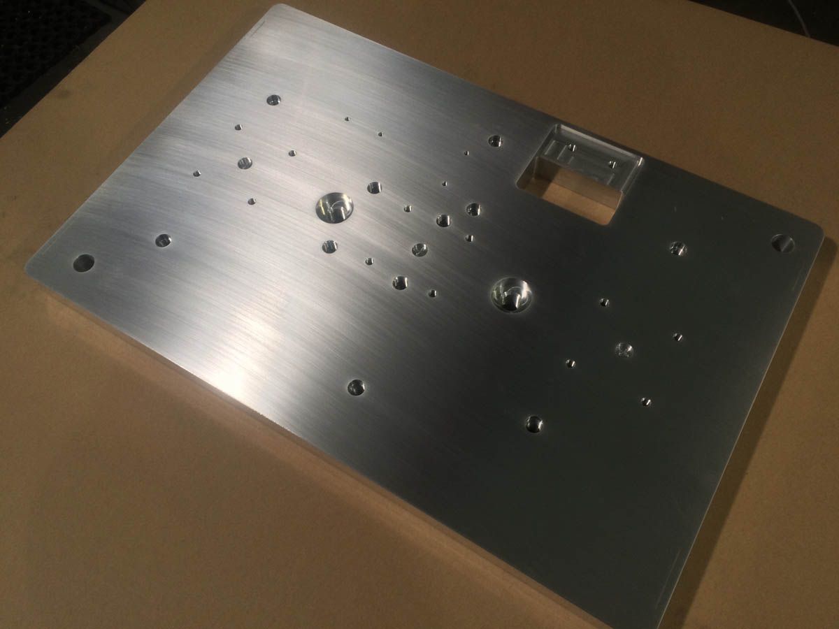 Aluminiumplatte mit verschiedenen Bohrungen und einem rechteckigen Ausschnitt.