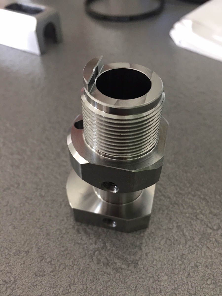 Metallbauteil mit Innenbohrung, Außengewinde und Sechskantfuß.