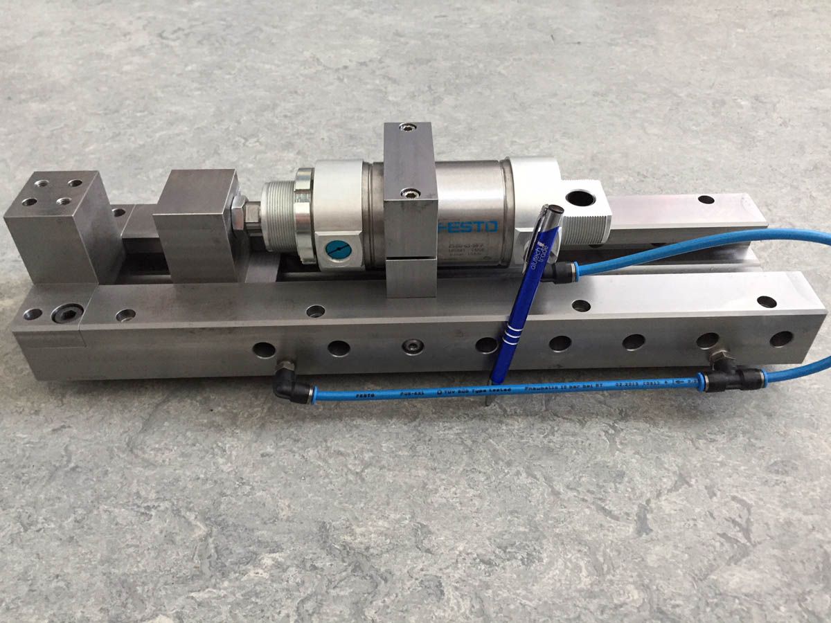 Pneumatischer Stellantrieb auf Metallsockel, mit angeschlossenen blauen Luftleitungen.