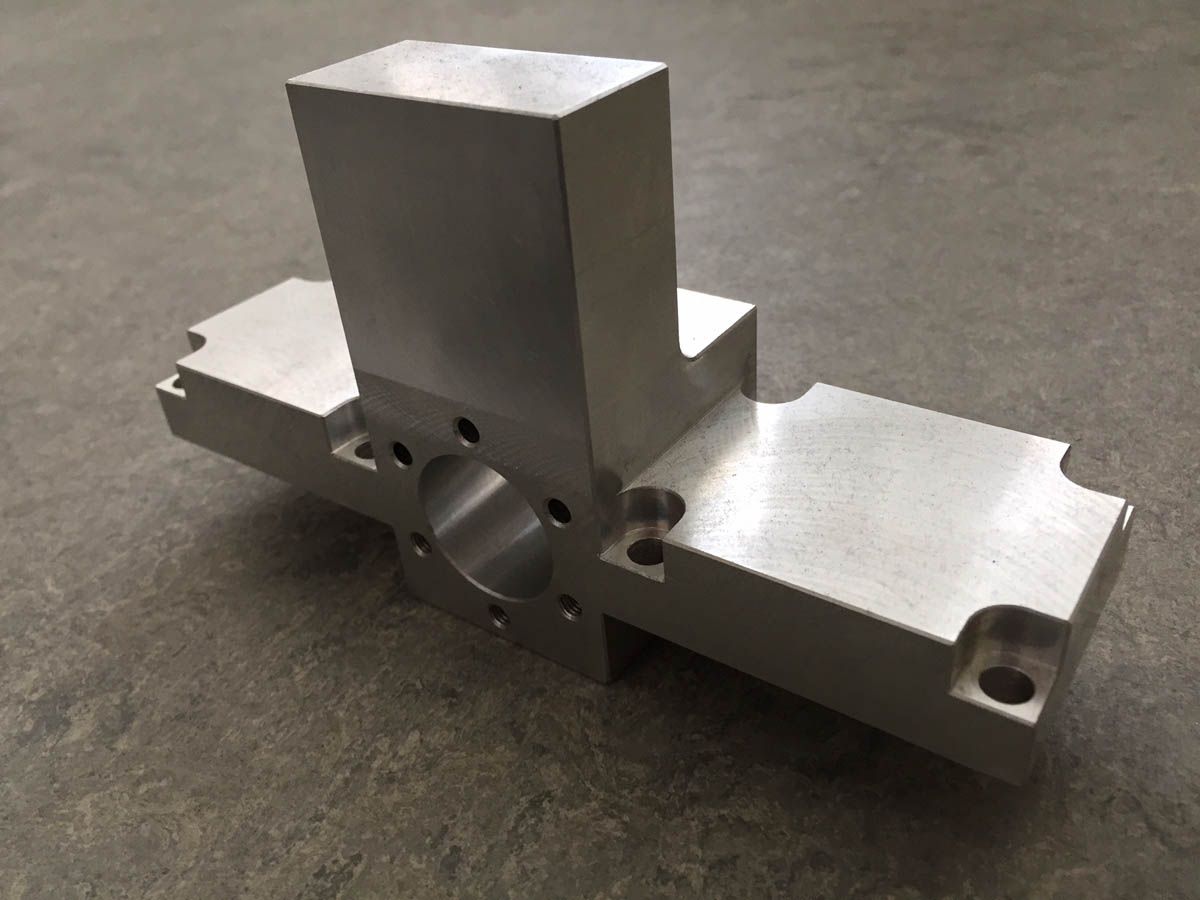 Silbernes, maschinell bearbeitetes Metallteil mit einer zentralen Säule und verlängerten Seitenplatten