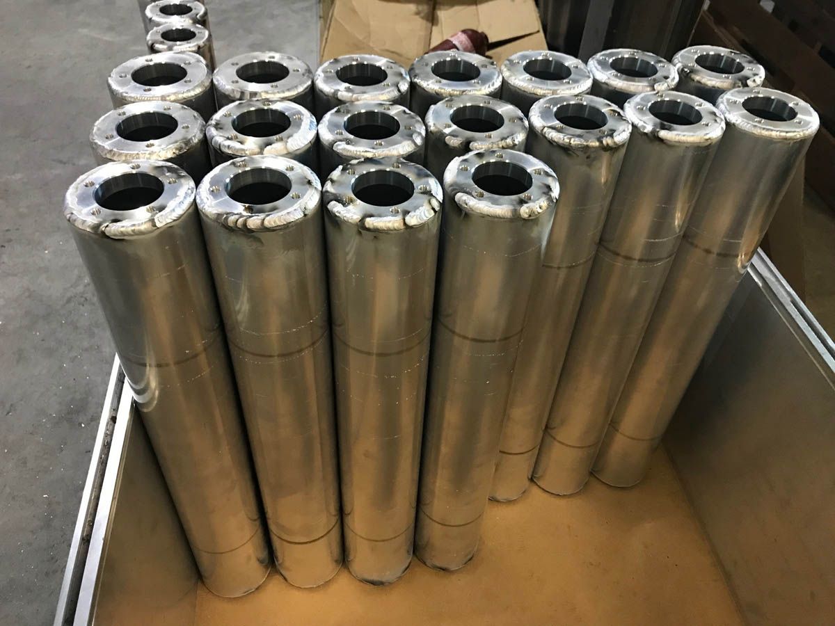 Mehrere zylindrische Metallgegenstände mit kreisförmigen Öffnungen in einem Aufbewahrungsbehälter.