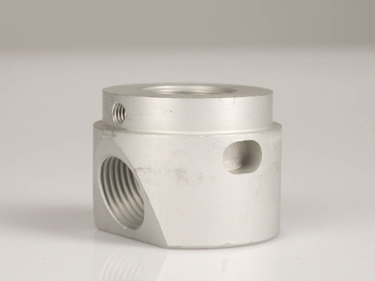 Silberfarbenes Metallarmatur mit drei Anschlüssen, zylindrische Form.