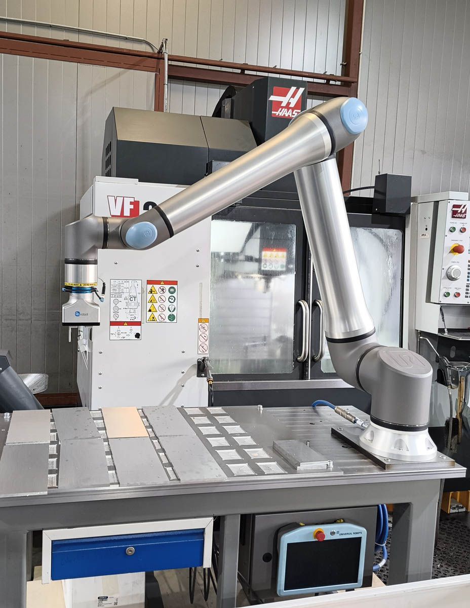 Ein Roboterarm lädt Teile in eine CNC-Maschine in einer Werkstatt.