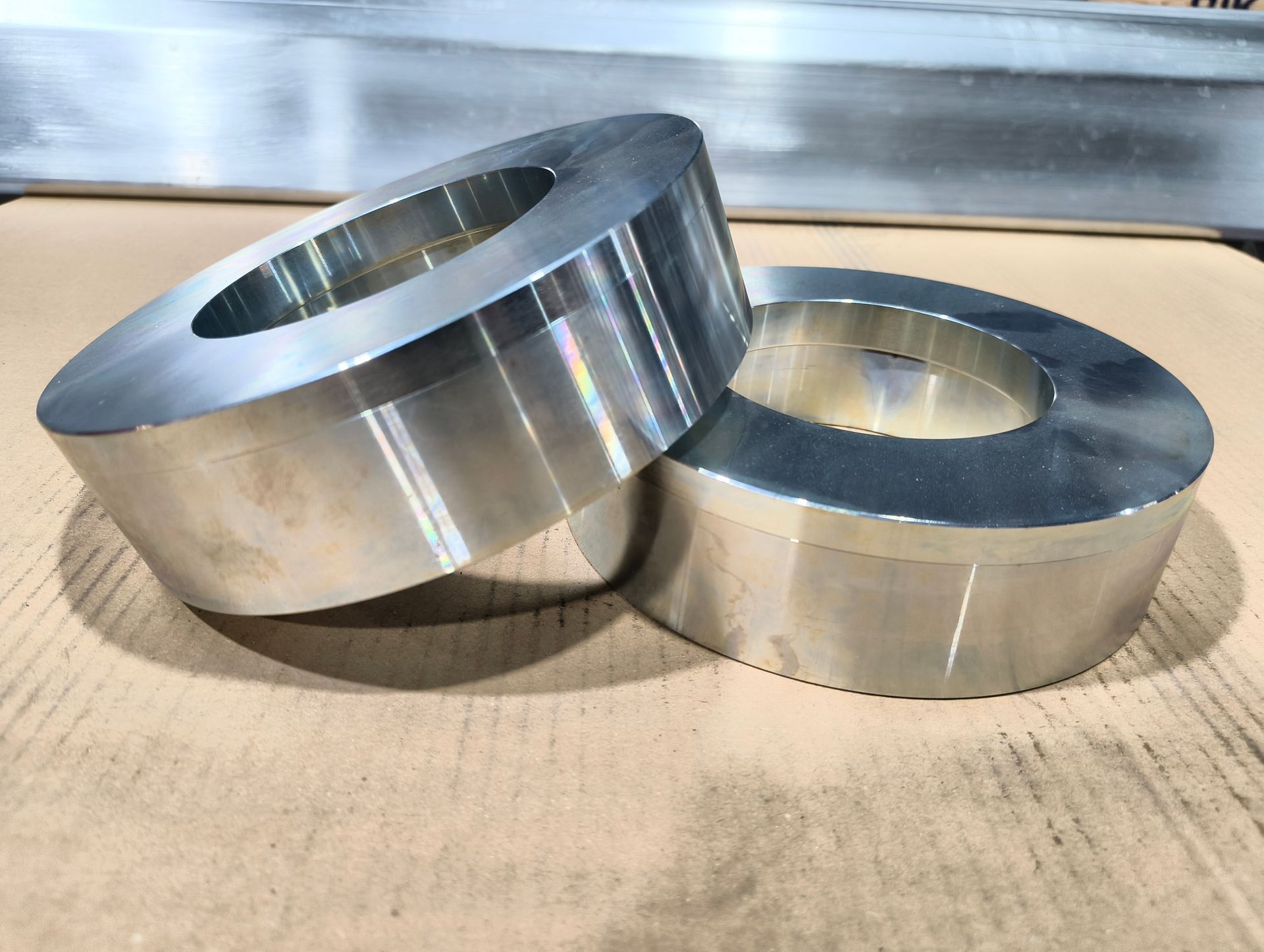 Zwei polierte, ringförmige Metallgegenstände auf einer Kartonoberfläche.