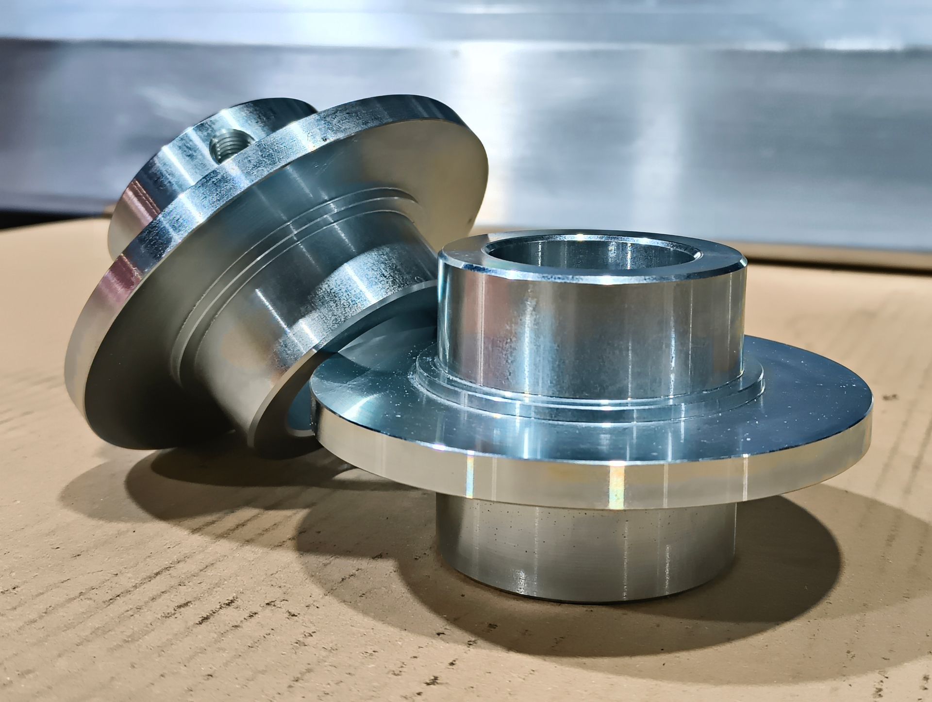 Zwei präzisionsgefertigte Metallnaben auf einer Kartonoberfläche.