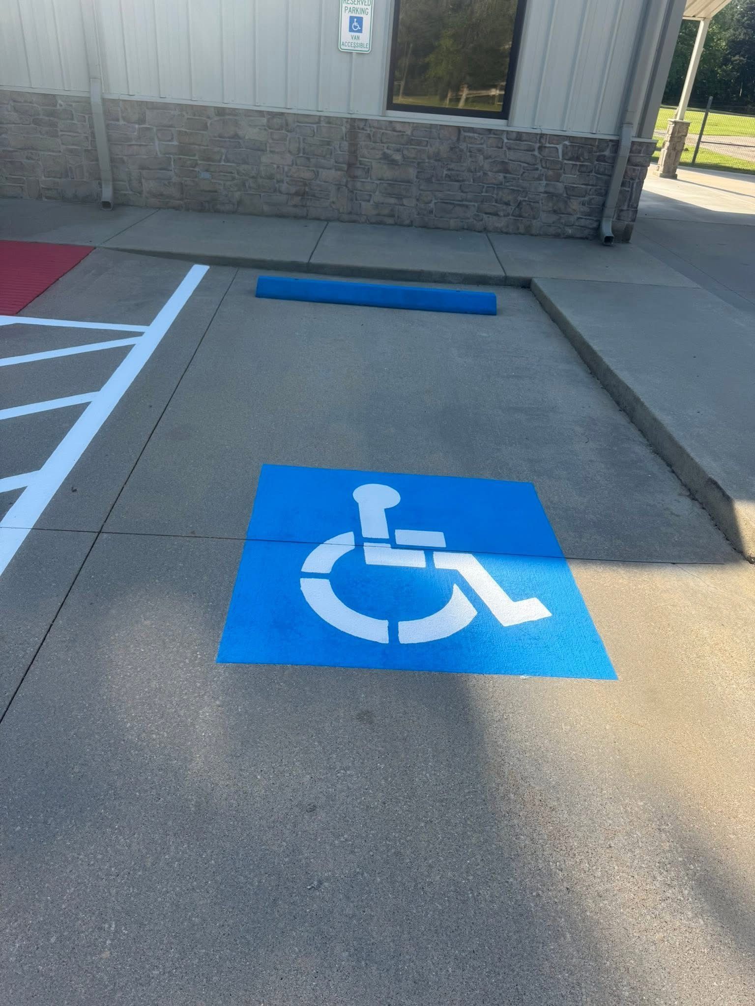A blue-painted handicap parking space on concrete, featuring a white international symbol of access.