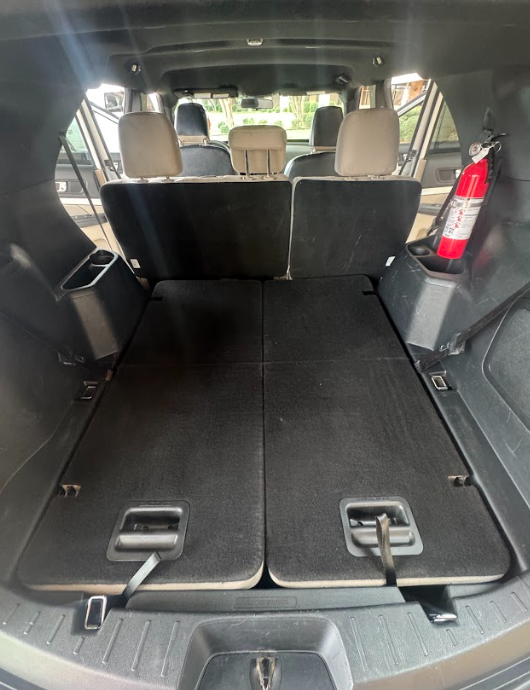 The interior cargo area of an SUV with the rear seats folded flat, featuring a fire extinguisher mounted on the side.