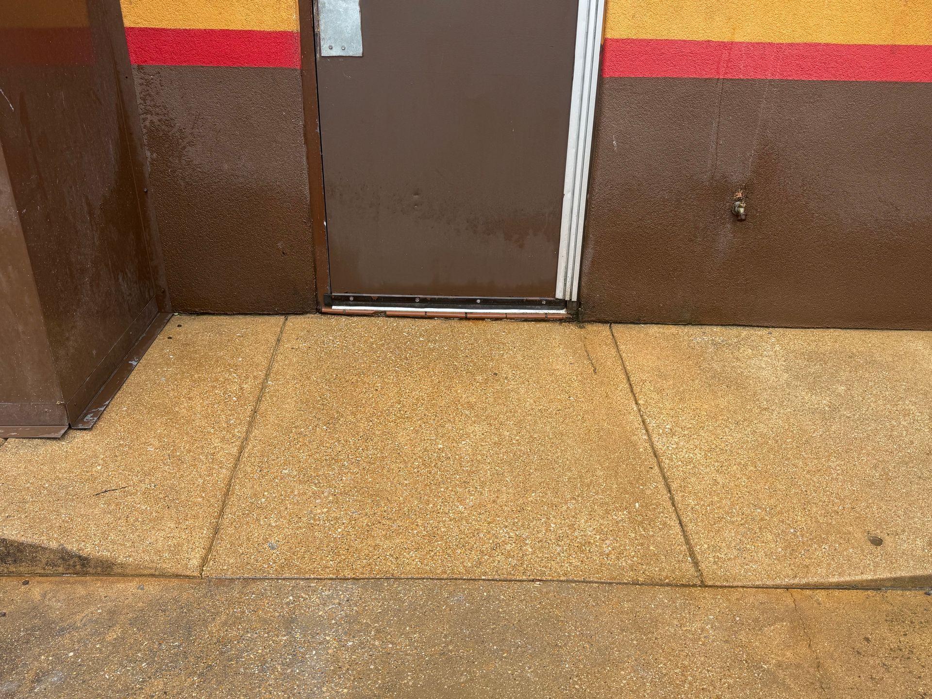Tiled floor and closed brown door in a hallway with red and yellow wall trim