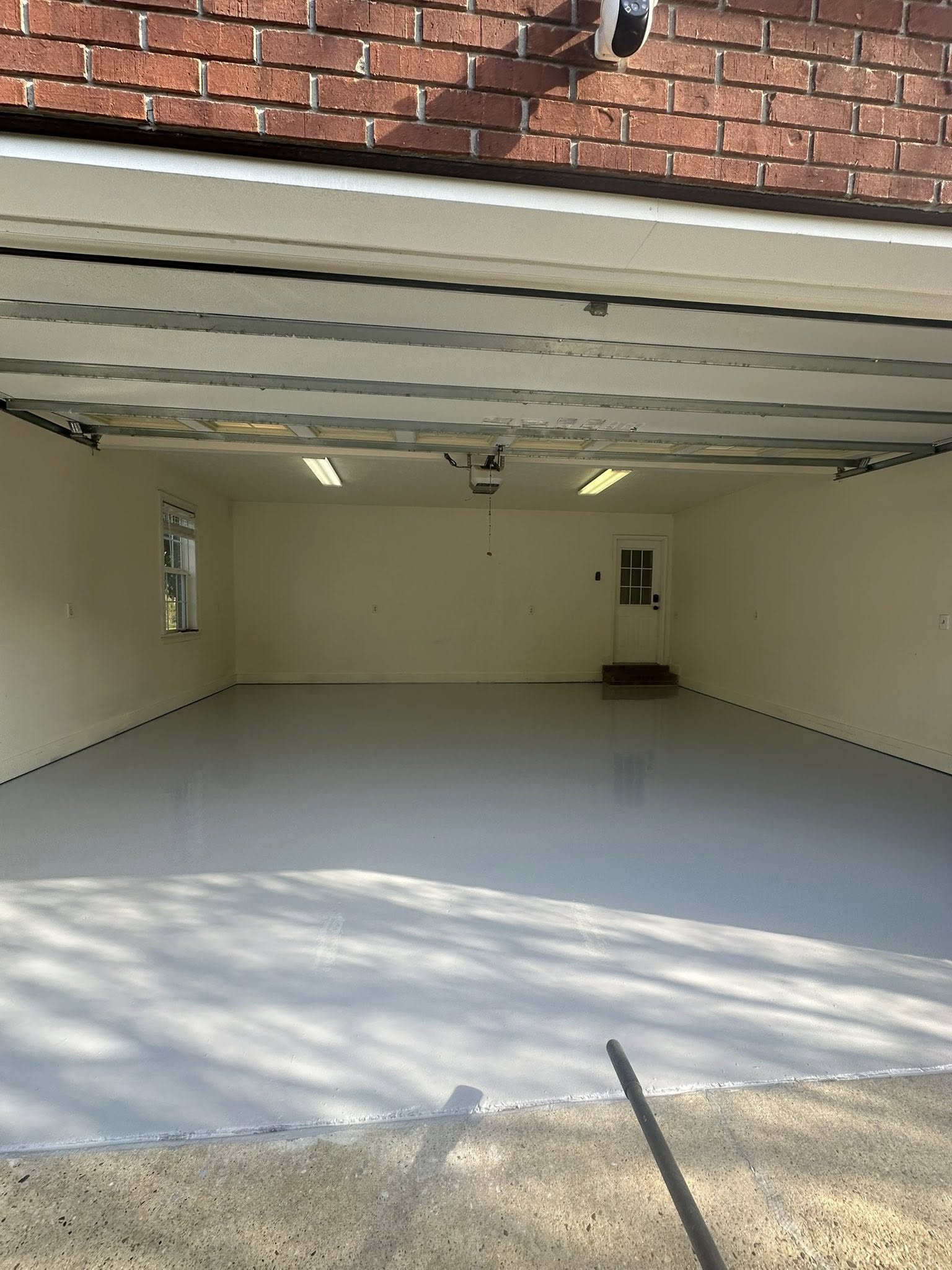 Open garage with white interior walls, closed overhead door, and brick exterior above