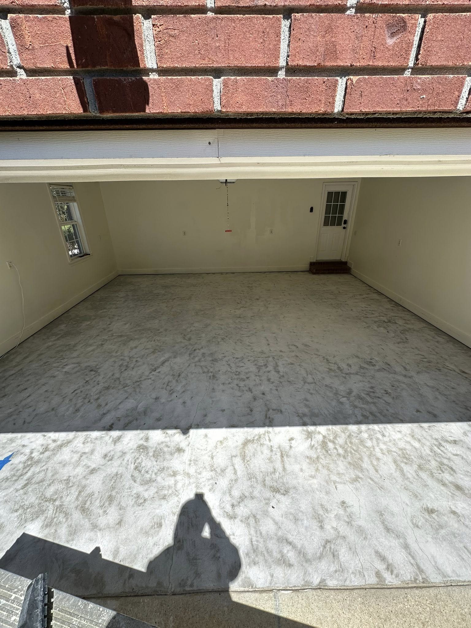 Empty concrete storage bay under a brick ledge, with beige walls and a shadowed floor.
