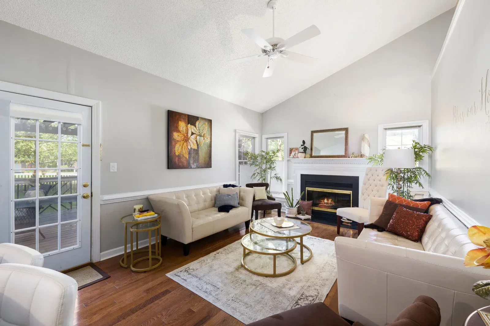 Living room with vaulted ceiling, fireplace, and two cream-colored sofas.
