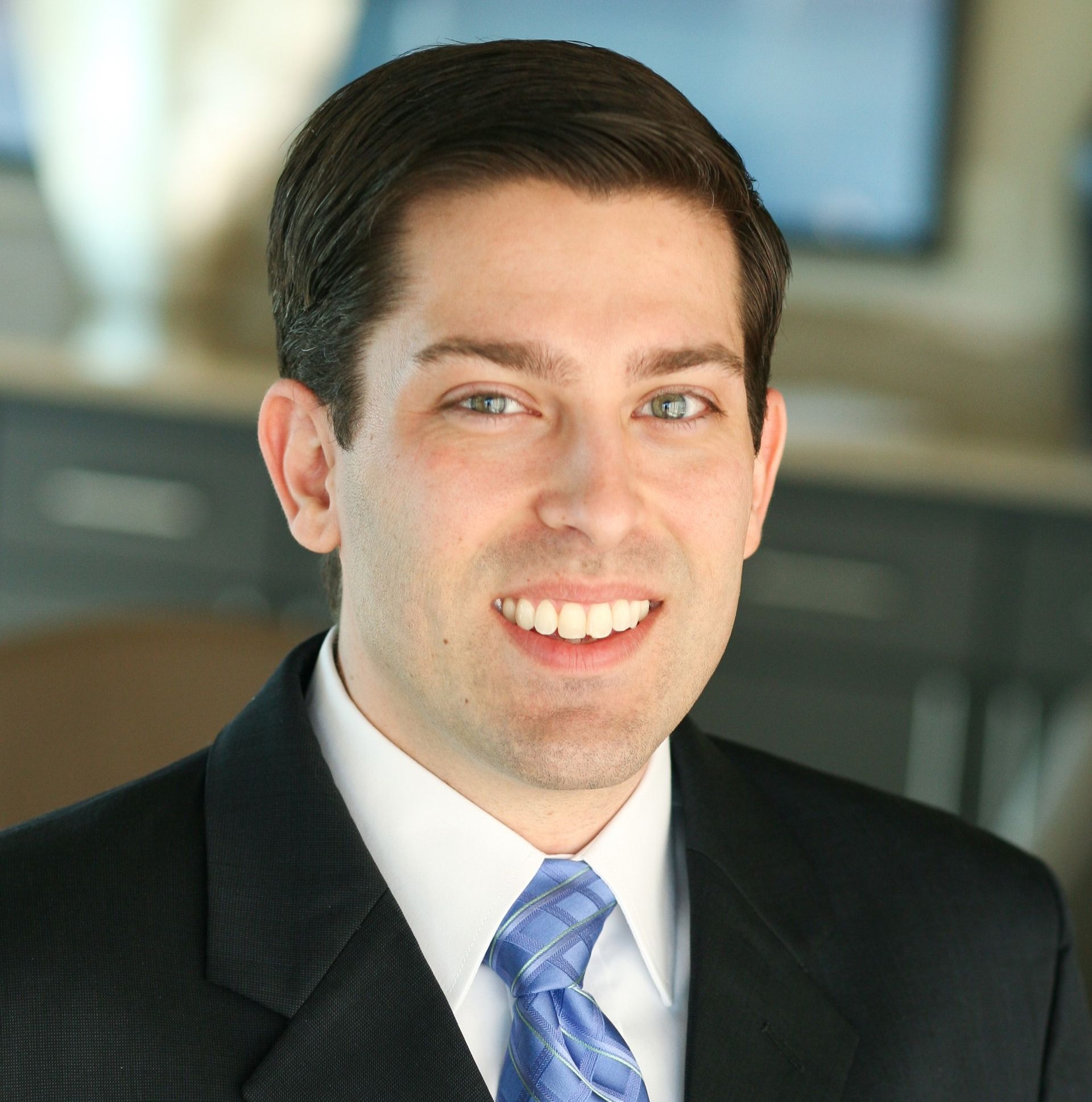 Matt Juren in suit smiling, indoors, with a blue tie.