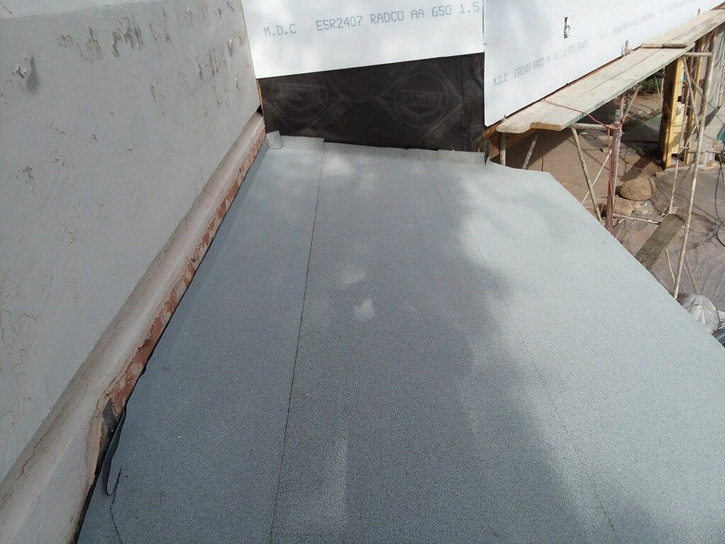 A gray carpet is being installed on the side of a building
