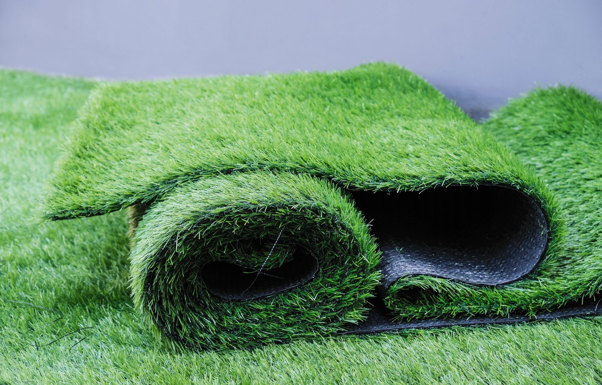 Rolled green artificial grass mat on a flat surface
