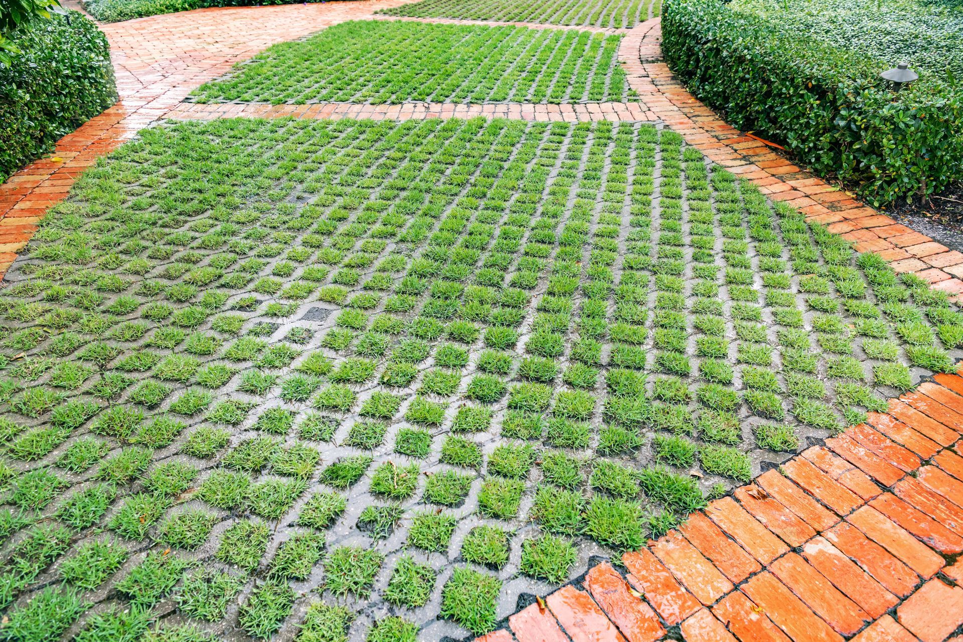 Green grass pavers bordered by red brick in a landscaped garden path