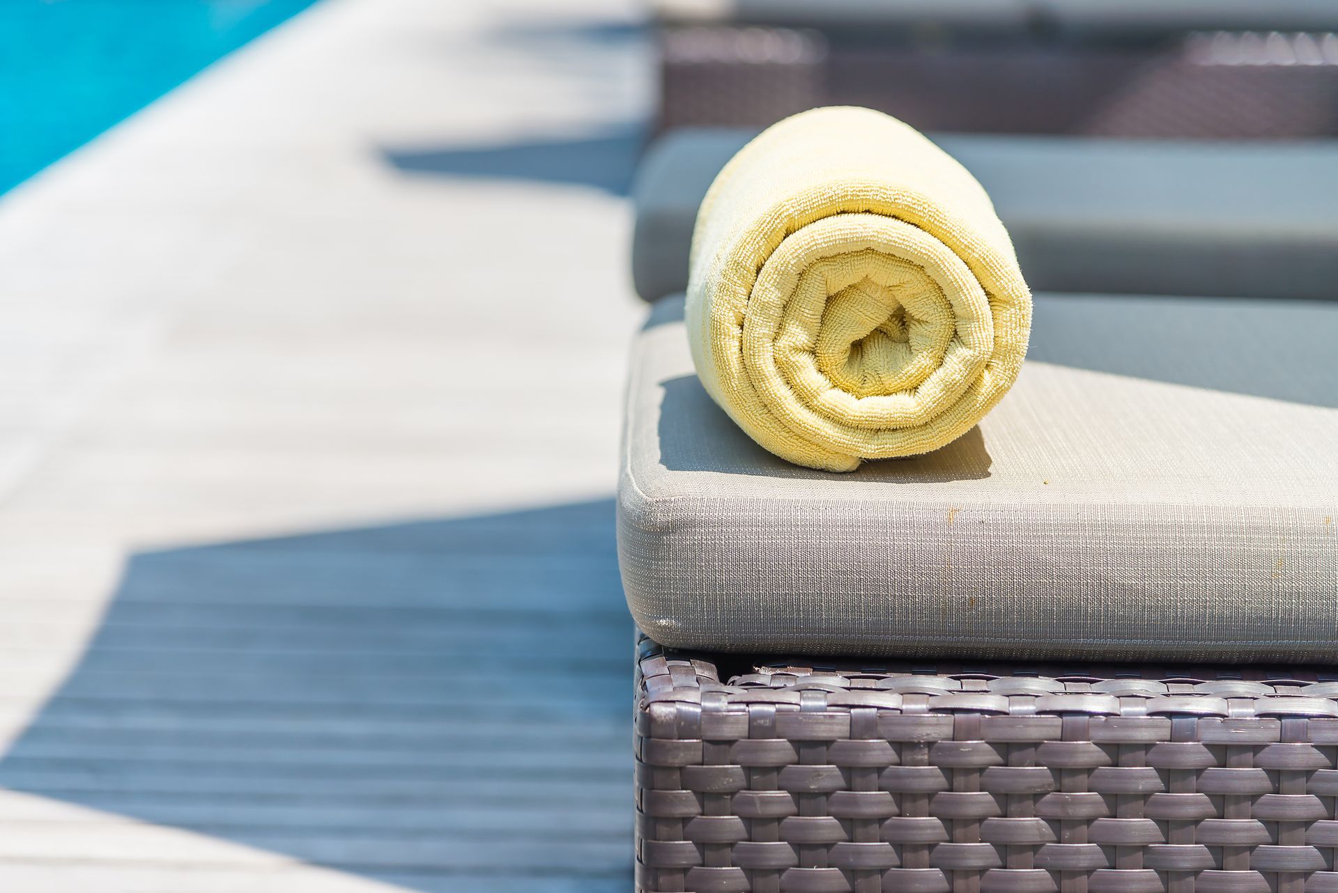 A towel is rolled up on a chair next to a pool.
