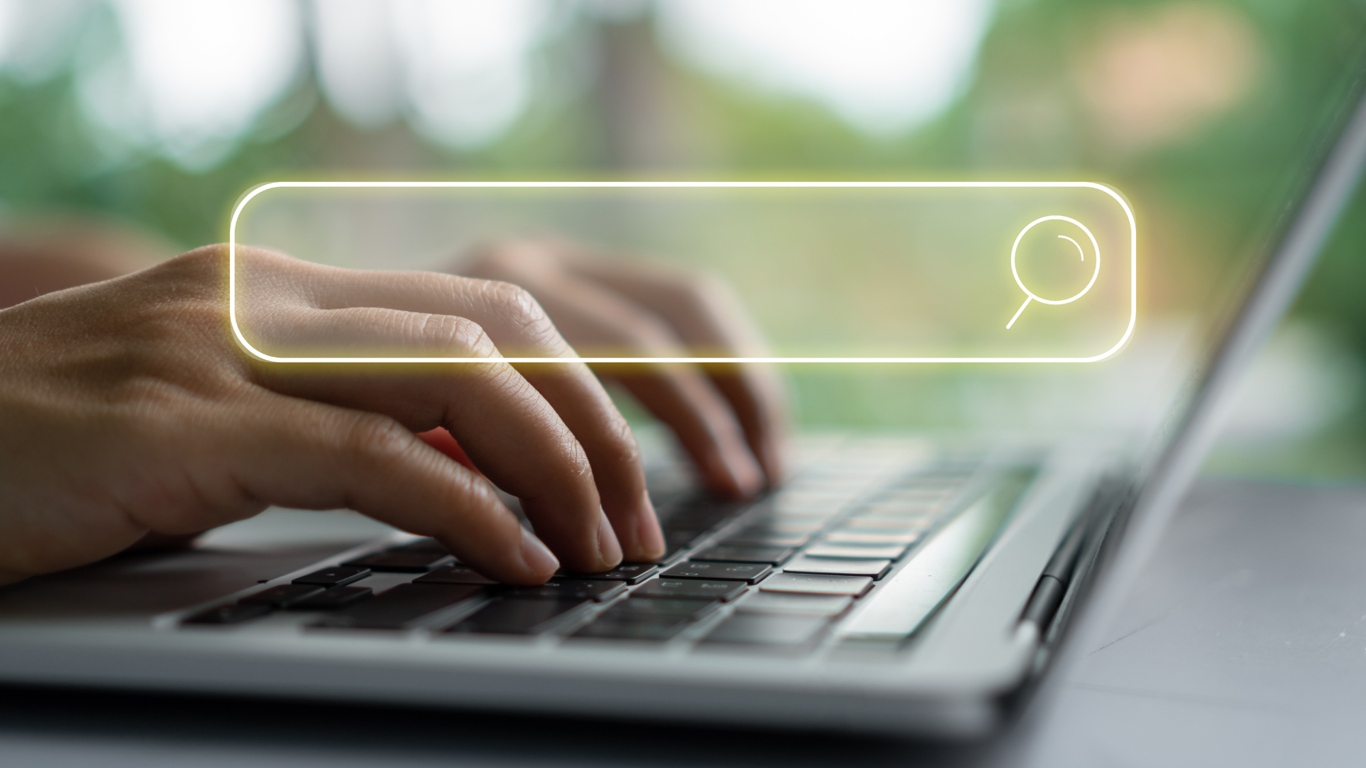 Person typing on laptop, holding phone, search bar overlay.