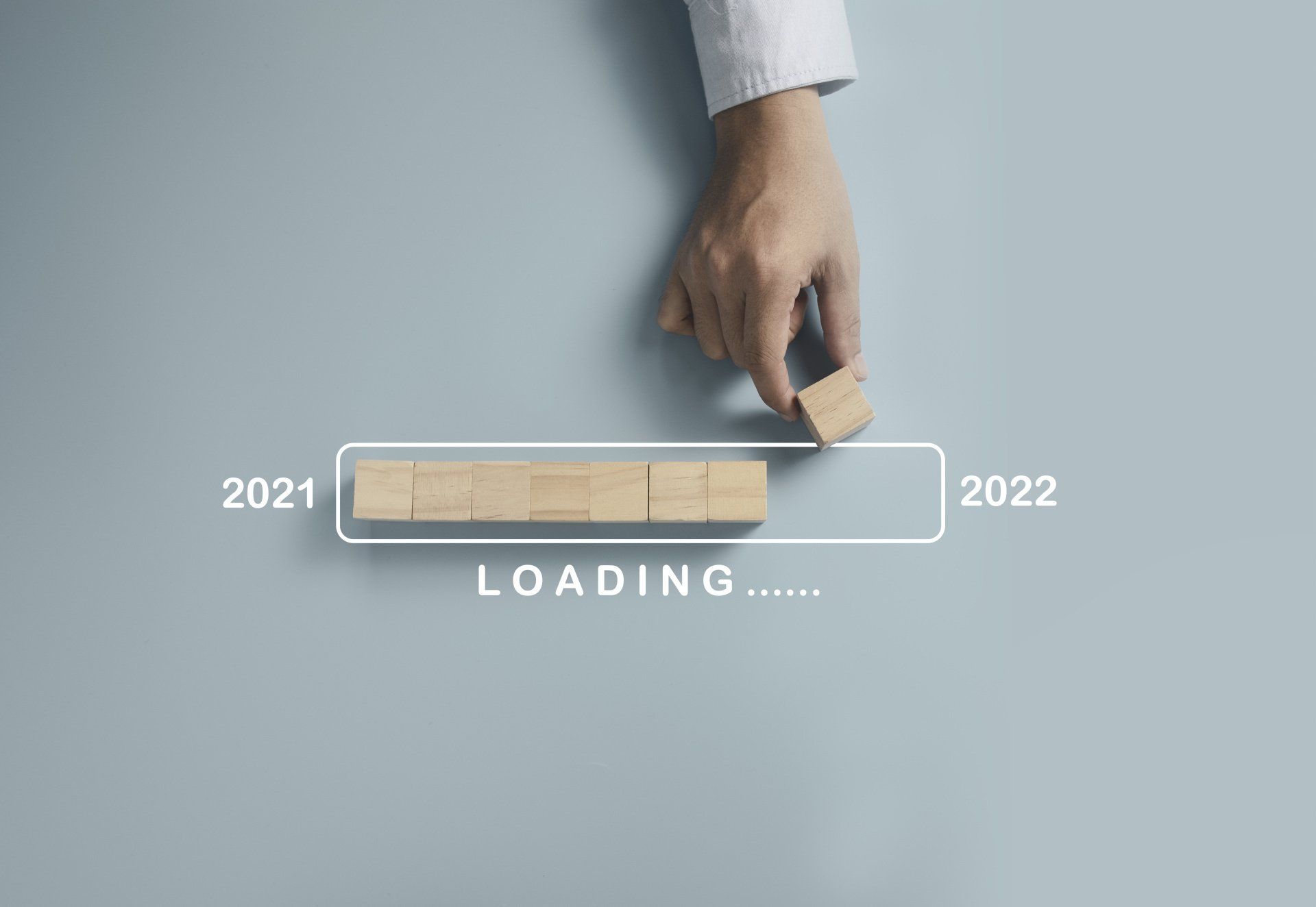 A hand is holding a wooden block next to a loading bar.