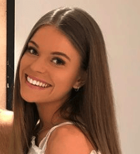 A woman with long hair is smiling and looking at the camera.