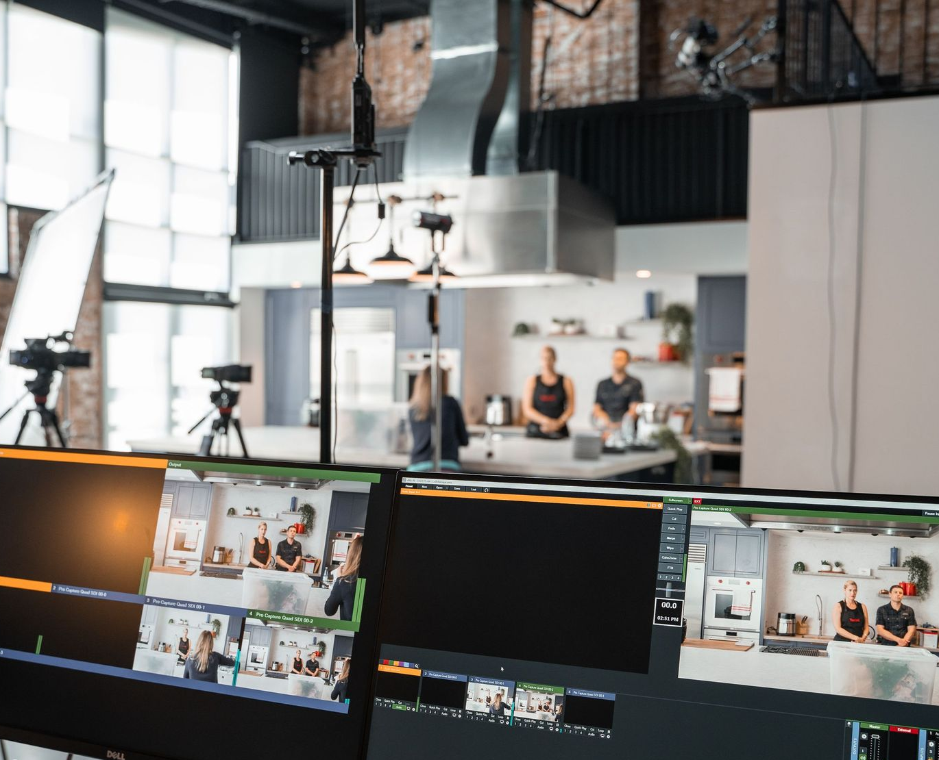 Live streaming setup in a studio, with multiple monitors showing camera feeds and people on set
