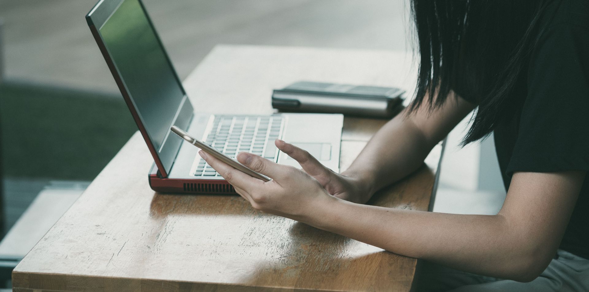 Person typing on a laptop at a table in a bright room