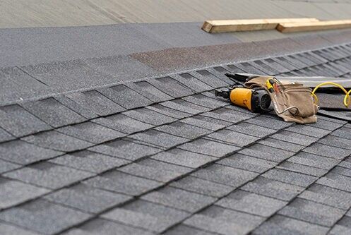 Roofing nailer and tool bag on a shingled roof during repair work