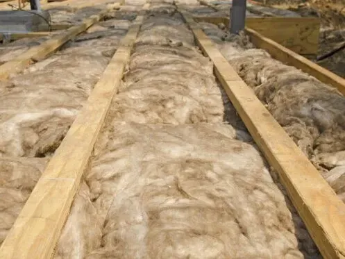 Insulated attic floor with exposed fiberglass batts and wooden joists