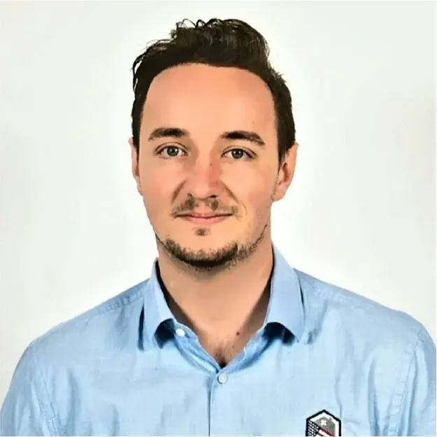 Headshot of a smiling person in a light blue button-up shirt against a white background