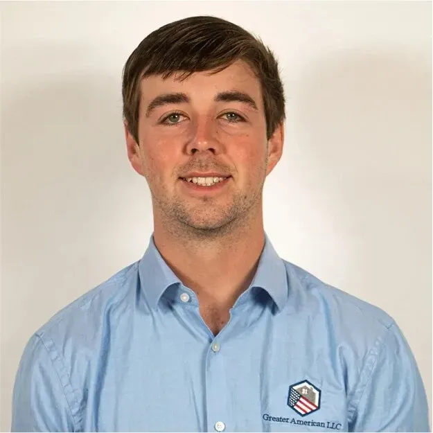 Portrait of a smiling man in a light blue button-down shirt against a plain white background