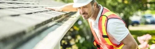 Worker in safety vest and hard hat inspecting solar panels on a rooftop